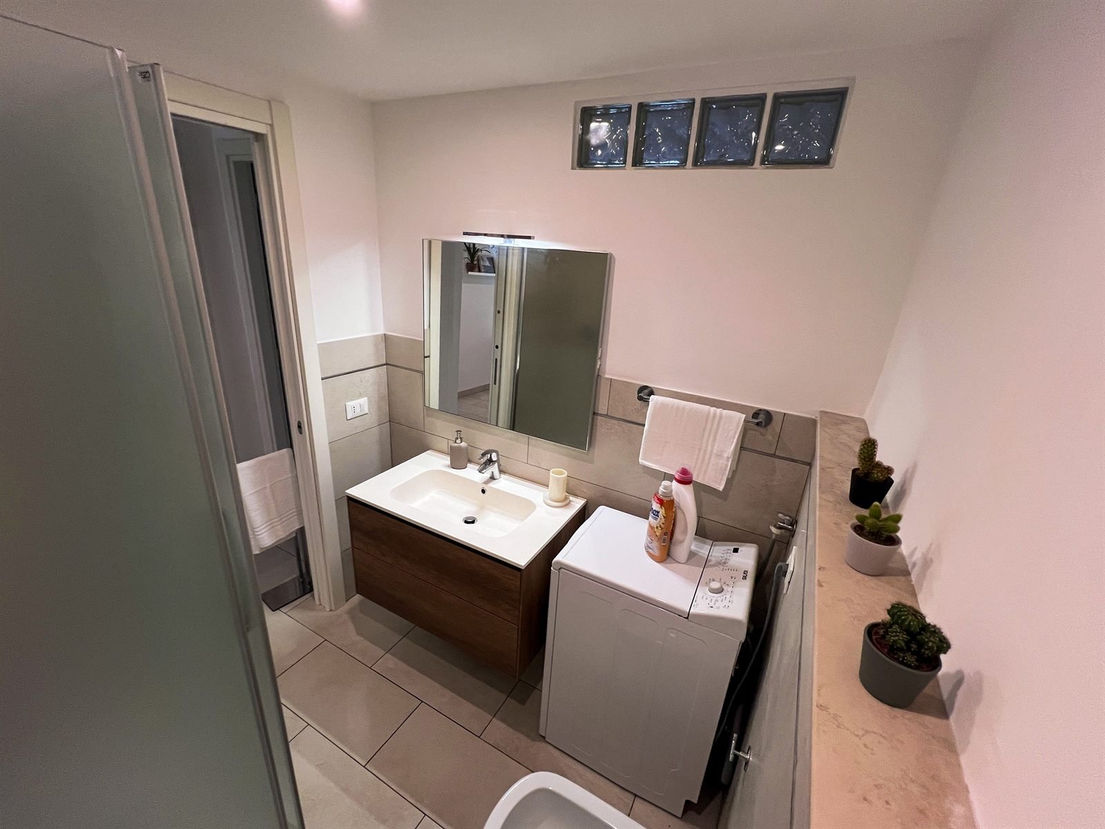 Bagno con mobile in legno e lavatrice